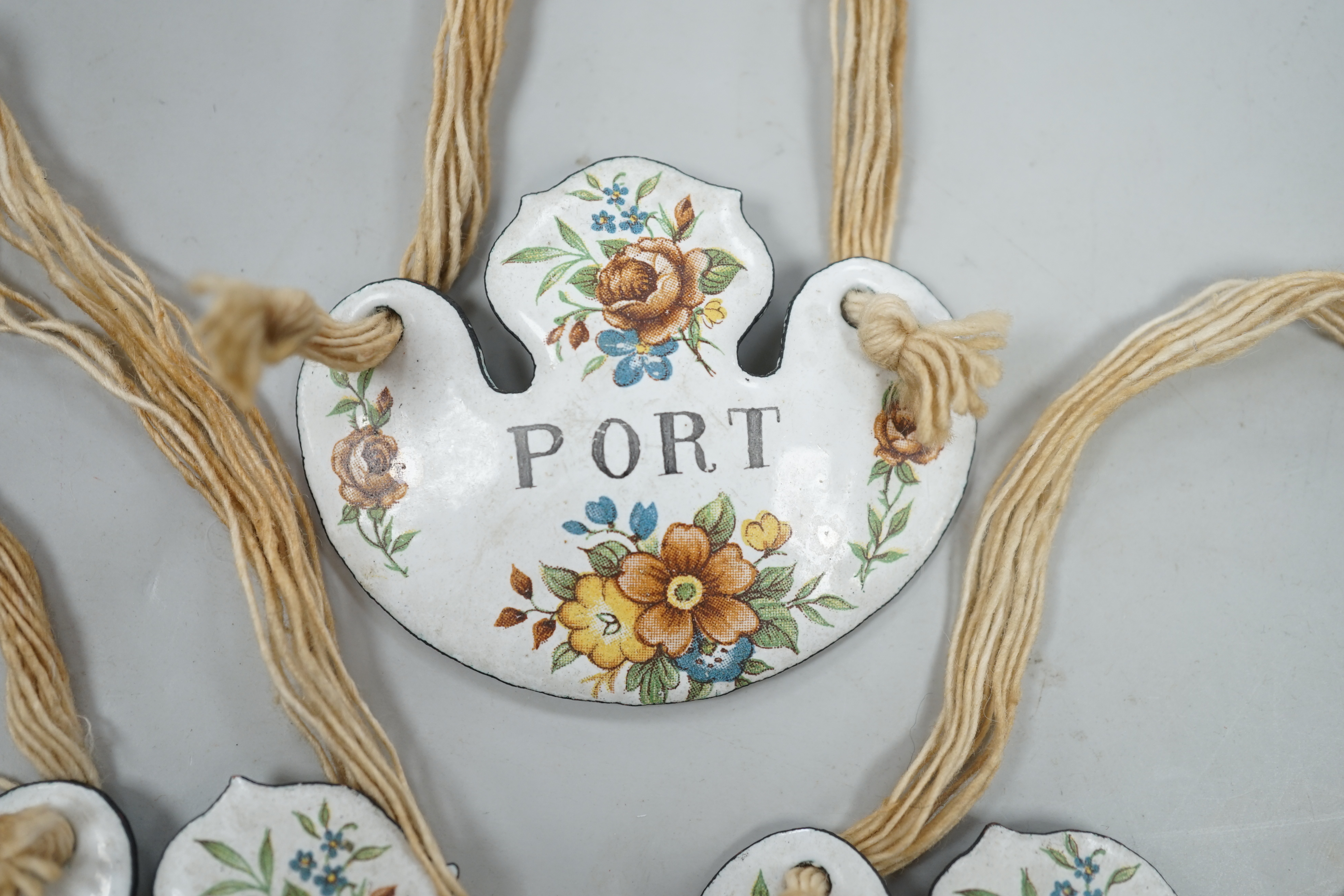 A group of three enamelled bottle labels - ‘rum’, ‘gin’ and ‘port’